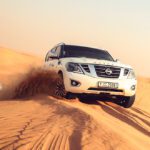 Sunrise over the sand dunes in Al Awir during a morning desert safari, featuring a desert adventurer sandboarding down a dune