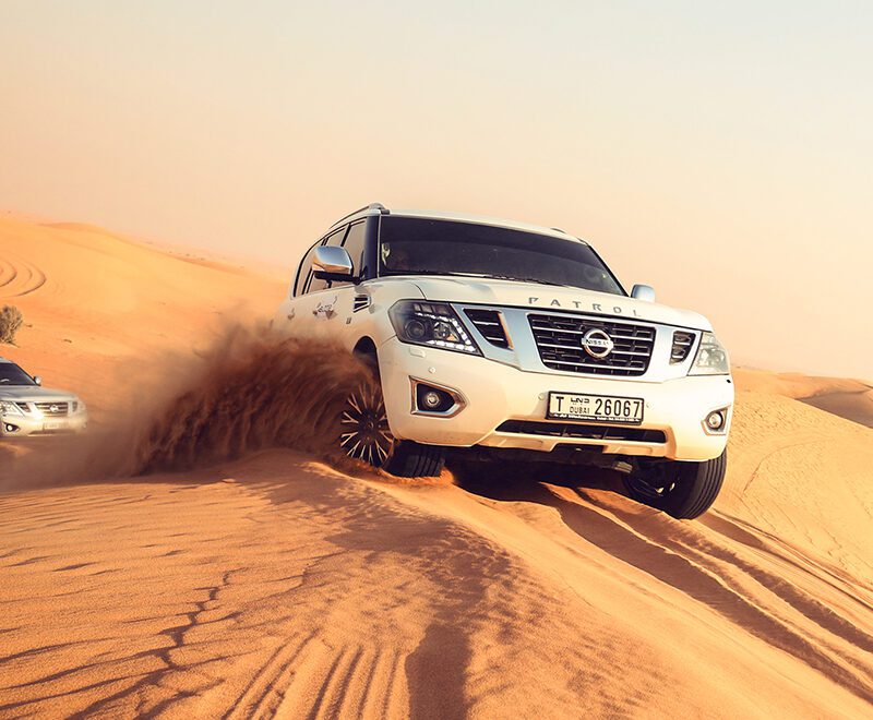 Sunrise over the sand dunes in Al Awir during a morning desert safari, featuring a desert adventurer sandboarding down a dune